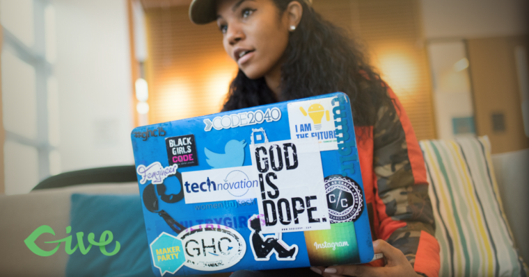A woman with a laptop with many stickers on it.